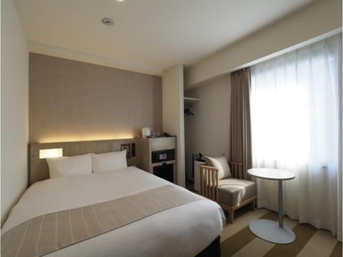 a bedroom with a bed and a chair and a window at Far East Village Hotel Yokohama - Vacation STAY 35241v in Yokohama