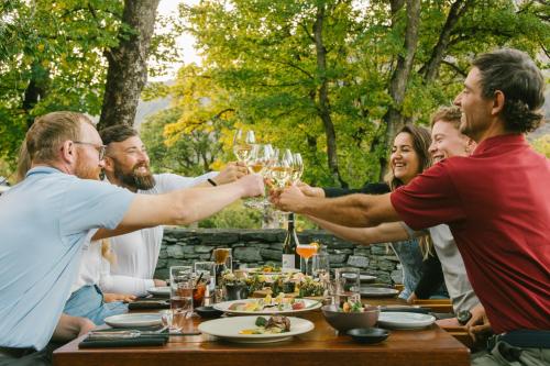a group of people raising their glasses at a table at Millbrook Resort in Arrowtown