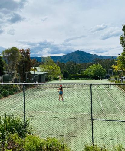 a person is standing on a tennis court at The Dairy at Cambewarra Estate Winery in Camberwarra