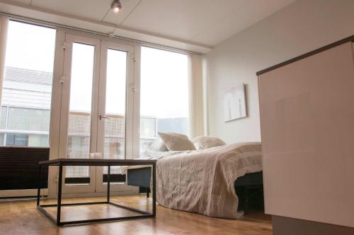 Un dormitorio con una cama y una mesa y ventanas. en Cozy Studio in Central Tromsø, en Tromsø