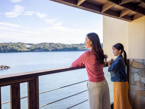 a woman and a child standing on a balcony looking at the water at Haifu in Shima