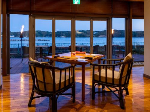 a wooden table and chairs with a view of the water at Haifu in Shima