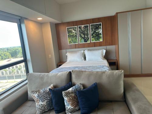 a bedroom with a bed and a couch with pillows at Tropical executive vista Rio in Manaus