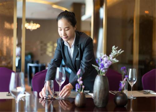 a woman sitting at a table with wine glasses at Pullman Tangshan in Tangshan