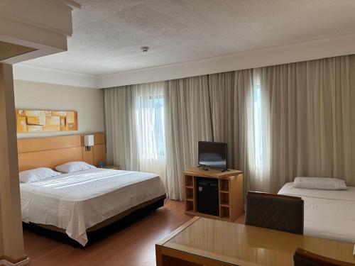 a hotel room with two beds and a television at Guarulhos flat services, aeroporto in Guarulhos
