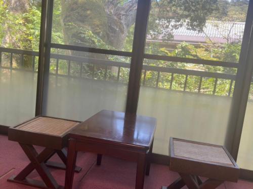 a table and a chair in front of a window at Onsen Yado Mizuguchi in Izu