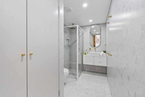 a bathroom with a toilet and a sink and a mirror at Oaklight on Truro - Steps to Torquay Beach and Dining in Torquay