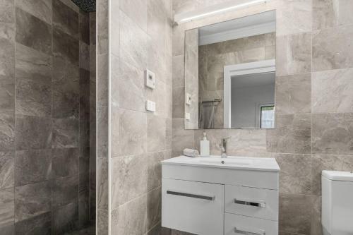 ein Badezimmer mit Waschbecken und Spiegel in der Unterkunft Surf Haven Escape - Modern and Central in Thirroul in Thirroul