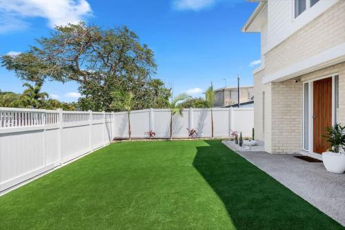 a backyard with a white fence and green grass at Hamptons House Family Retreat in Torquay