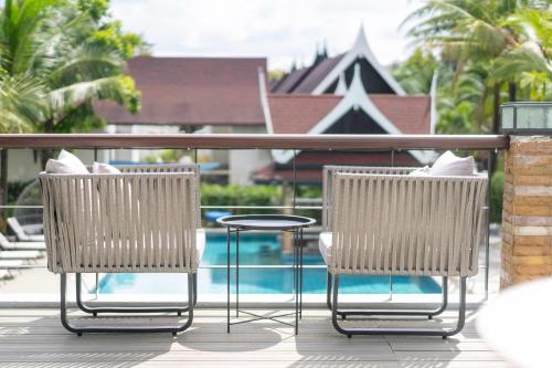 two chairs and a table on a balcony with a pool at Howard Johnson by Wyndham Phuket Naiyang in Thalang