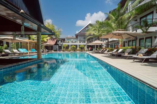 a swimming pool with chairs and umbrellas at a hotel at Howard Johnson by Wyndham Phuket Naiyang in Thalang