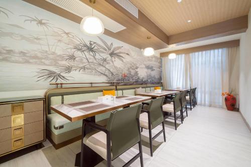 a restaurant with tables and chairs and a painting on the wall at Howard Johnson by Wyndham Phuket Naiyang in Thalang