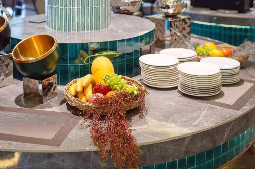 a table with a basket of fruits and plates at Howard Johnson by Wyndham Phuket Naiyang in Thalang