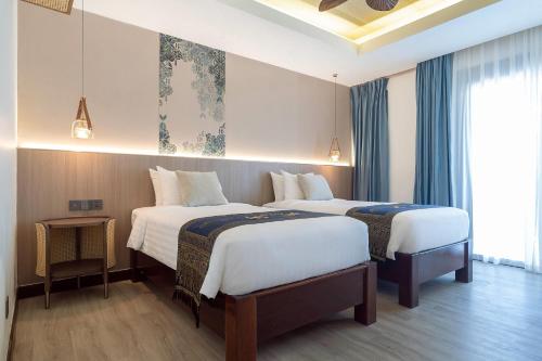 a hotel room with two beds and a window at Howard Johnson by Wyndham Phuket Naiyang in Thalang