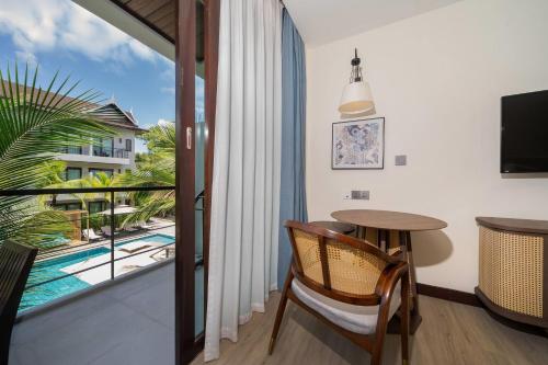 a room with a table and a balcony with a pool at Howard Johnson by Wyndham Phuket Naiyang in Thalang