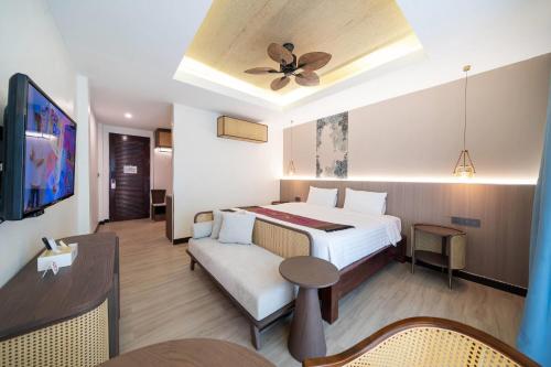 a hotel room with a bed and a ceiling fan at Howard Johnson by Wyndham Phuket Naiyang in Thalang