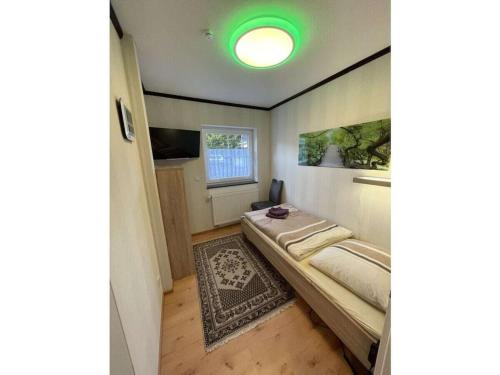 a small bedroom with a bed and a green light at Holiday Home Deluxe in Kleinweidelbach