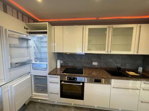 a kitchen with white cabinets and a stove top oven at Holiday Home Deluxe in Kleinweidelbach