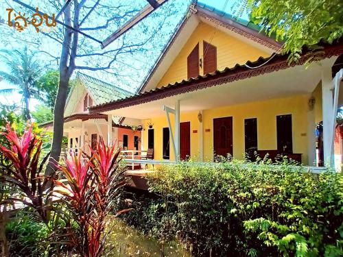 a yellow house with red shuttered windows and plants at Aioun At Amphawa in Ban Bang Khan Taek (1)