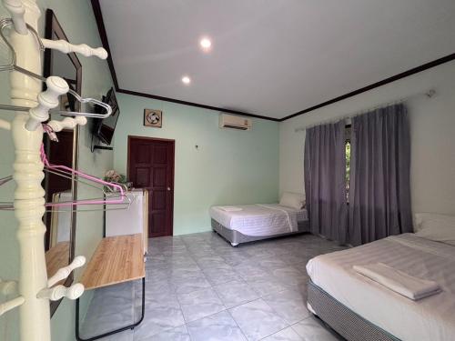 a room with two beds and a table in it at Aioun At Amphawa in Ban Bang Khan Taek (1)