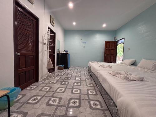a bedroom with two beds and a floor with a rug at Aioun At Amphawa in Ban Bang Khan Taek (1)