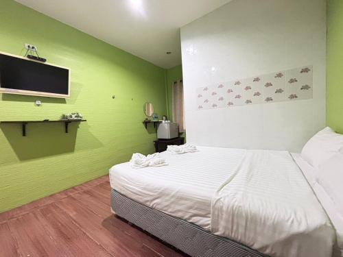 a bedroom with a white bed and a green wall at Aioun At Amphawa in Ban Bang Khan Taek (1)
