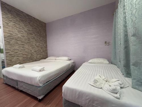 two beds in a hotel room with white sheets at Aioun At Amphawa in Ban Bang Khan Taek (1)