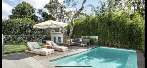 a swimming pool with two chairs and an umbrella next to at 6 Bedroom Californian Bungalow in Melbourne
