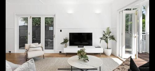 a white living room with a tv and a table at 6 Bedroom Californian Bungalow in Melbourne