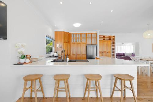 a kitchen with a white counter top and wooden stools at Esplanade Ease - Absolute Beachfront in Hervey Bay in Point Vernon