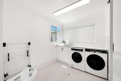 a white laundry room with two washer and dryer at Esplanade Ease - Absolute Beachfront in Hervey Bay in Point Vernon