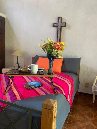 a table with a vase of flowers and a cross at Casa San Pablo in Valle de Bravo