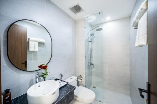 a bathroom with a sink and a mirror and a toilet at Tourane Boutique Hotel in Da Nang