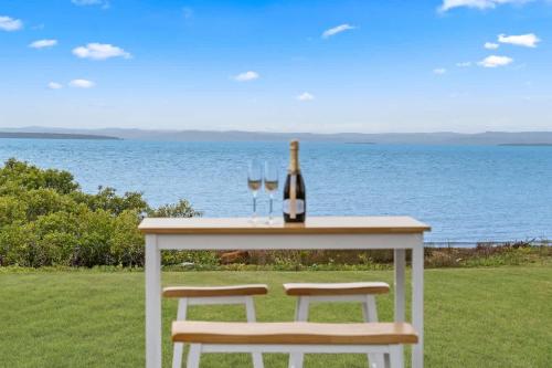 a table with two glasses and a bottle of wine at Beachfront Hervey Bay Homestead in River Heads