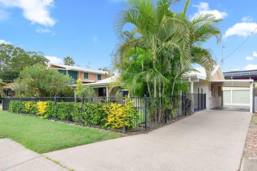 a palm tree in front of a house with a fence at Kiesha House Beachfront Serenity in Point Vernon