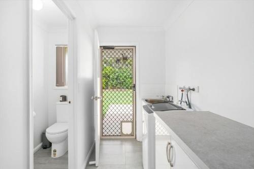 a white bathroom with a toilet and a sink at Kiesha House Beachfront Serenity in Point Vernon