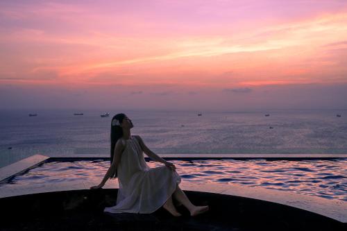 a woman sitting in a pool watching the sunset at OYSTER BAY HOTEL VUNG TAU in Vung Tau