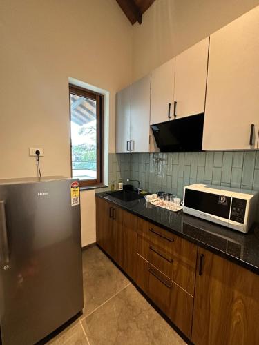 a kitchen with a refrigerator and a microwave at Trabalho de Amor in Benaulim