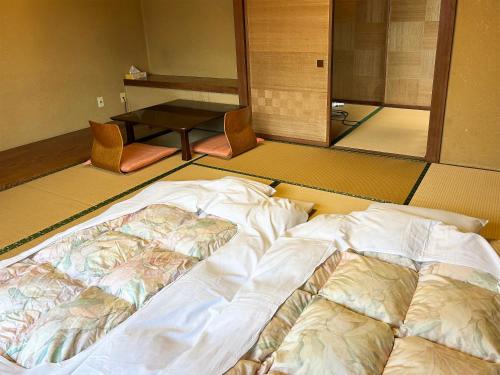 a large bed in a room with a table at 割烹旅館月茂登 in Kakegawa