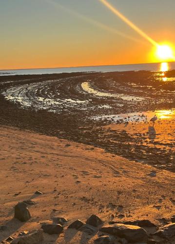 a sunset on a beach with the ocean at Sunset Shores Escape in Point Vernon