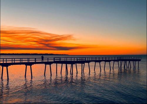 a person standing on a pier in the water at sunset at Sunset Shores Escape in Point Vernon