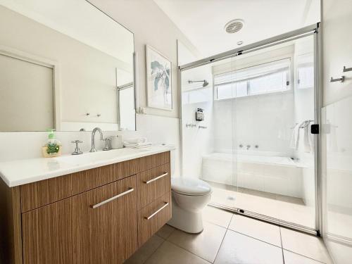 a bathroom with a sink and a toilet and a shower at Villa Oceania at Caves Beach Villas in Caves Beach
