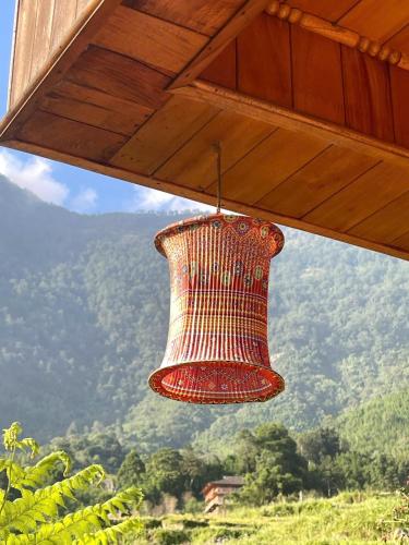 a red chandelier hanging from a roof with a mountain at Hmong Farmstay in Sa Pa