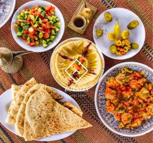 a table topped with plates of food and salads at BUBBLES LUXURY CAMp in Wadi Rum