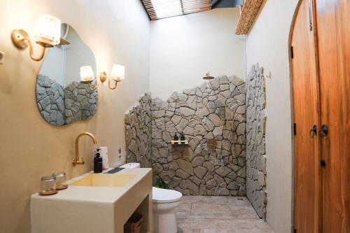 a bathroom with a sink and a stone wall at Ubu Villa Lemme with Rustic Mediterranean Style in Adi Sutjipto