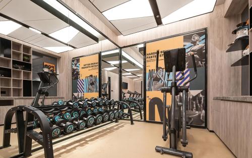 重慶市にあるThe Mustel Hotel Chongqing Hongyadongのトレッドマシンと壁にポスターが貼られたジム