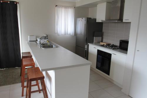 a white kitchen with a sink and a refrigerator at Malmsbury Cottage in Malmsbury