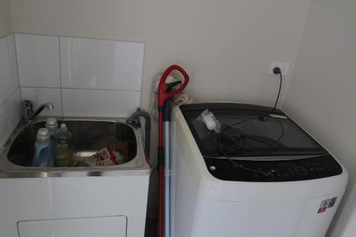 a kitchen with a sink and a red vacuum at Malmsbury Cottage in Malmsbury