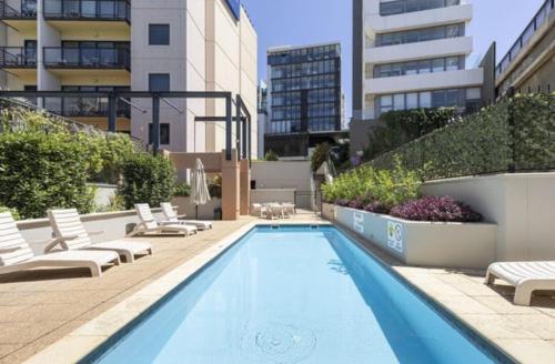 a swimming pool with lounge chairs and a building at City Lights Retreats - 2 Bedroom, 1 Bathroom in Perth