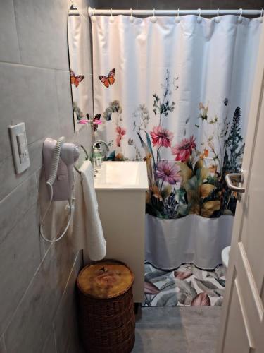 a bathroom with a sink and a shower curtain with butterflies at Asturiano 6 Miramar in Miramar